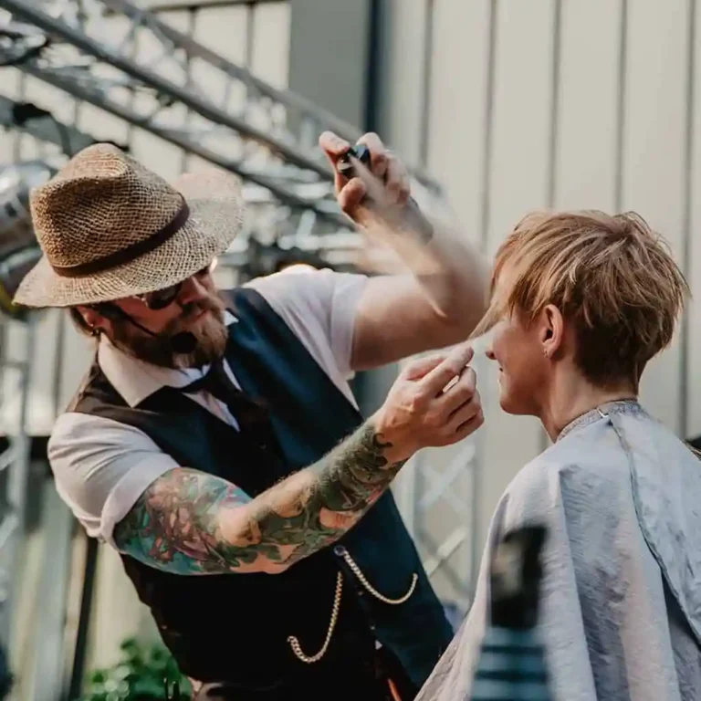 Friseur mit Hut schneidet das Haar eines Kunden während einer Frisurenpräsentation.