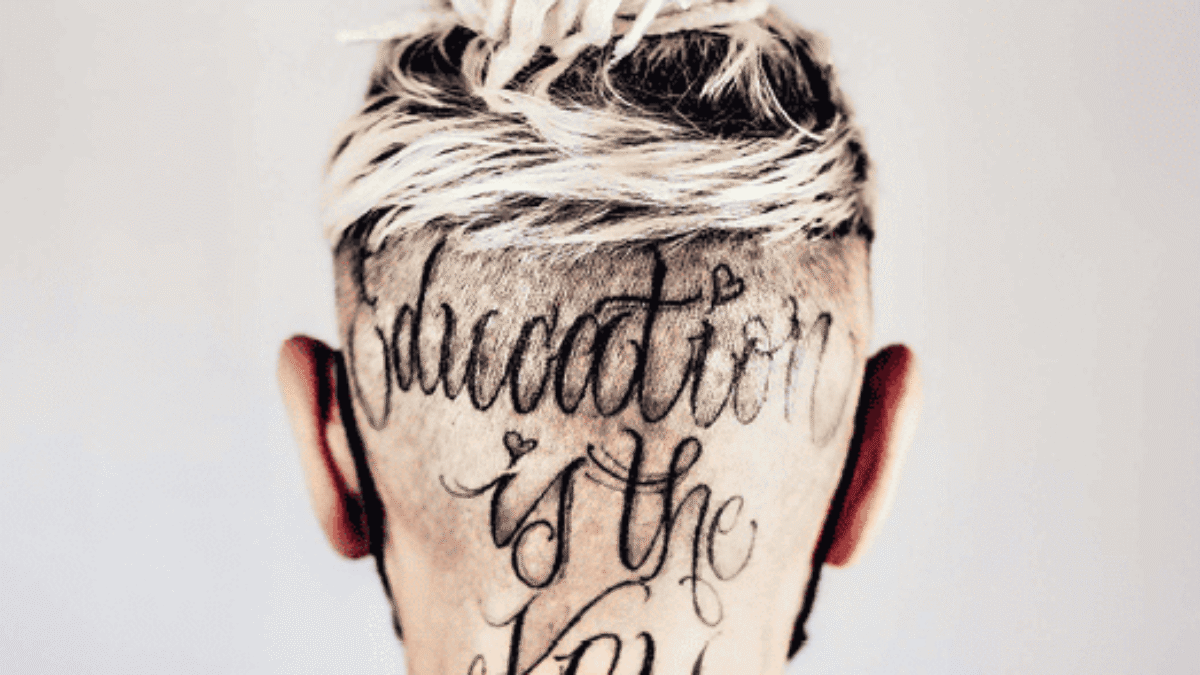 Hinteransicht eines Kopfes mit einem Haarschnitt und einer Tätowierung, die den Text 'education is the key' zeigt.