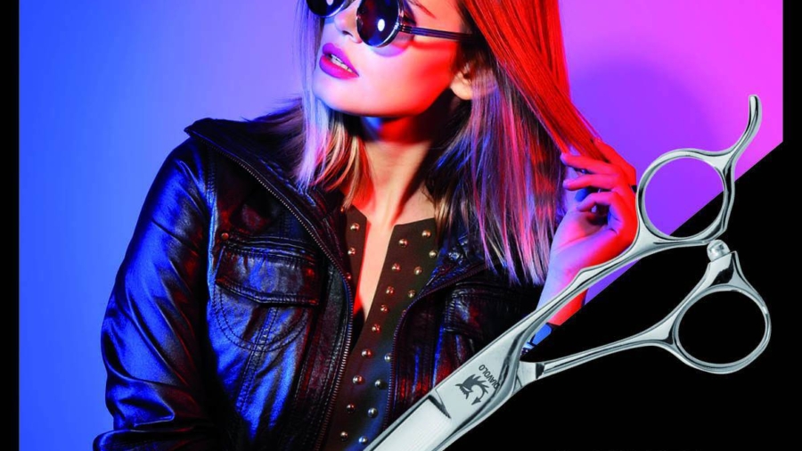 Model mit Sonnenbrille hält Haarsträhnen neben einer handgefertigten Friseurschere.