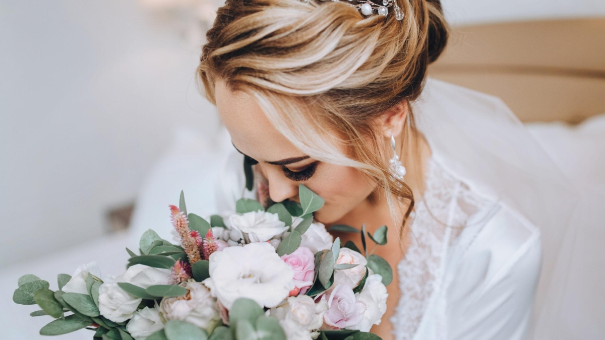 Braut mit einem bunten Blumenstrauß, der aus verschiedenen Blumen und grünem Blattwerk besteht.