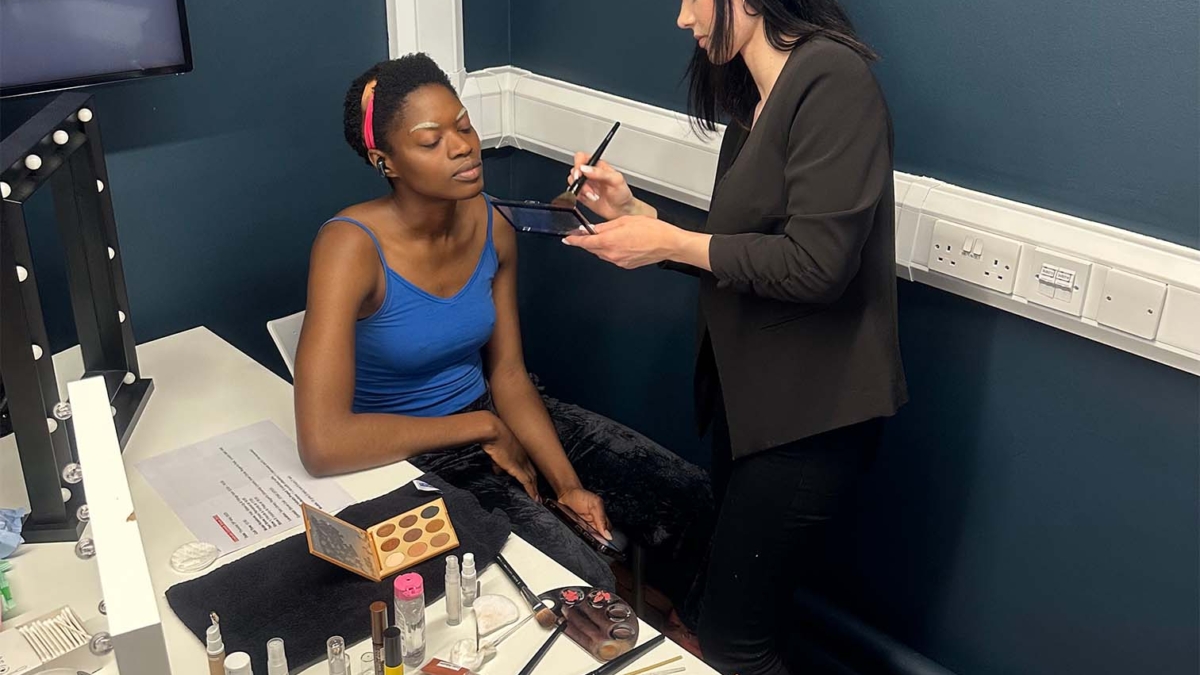 Ehemalige Schülerin der german beauty academy beim stylen eines Models backstage auf einer englischen Fashionshow