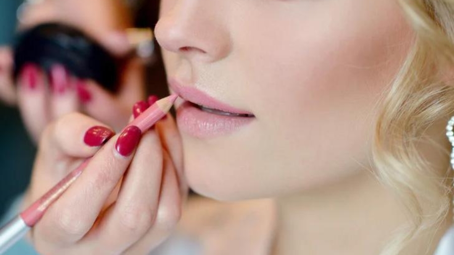 Eine Frau erhält Lippen-Make-up von einer anderen Person während einer Schönheitsanwendung.