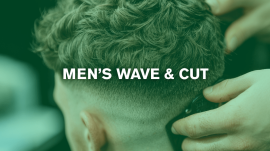 Basil Nissan demonstriert beim Seminar Men’s Wave & Cut eine moderne Herrenhaarschnitt- und Dauerwellen-Technik vor einem grün eingefärbten Hintergrund, mit Übungskopf und praktischer Demonstration