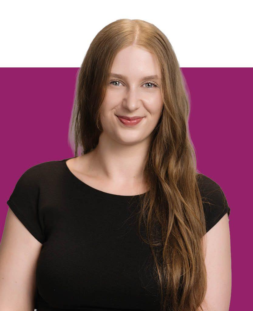 Dana Schädler mit langen braunen Haaren und schwarzem Oberteil lächelt vor einem weißen und violetten Hintergrund in der Teamvorstellung.